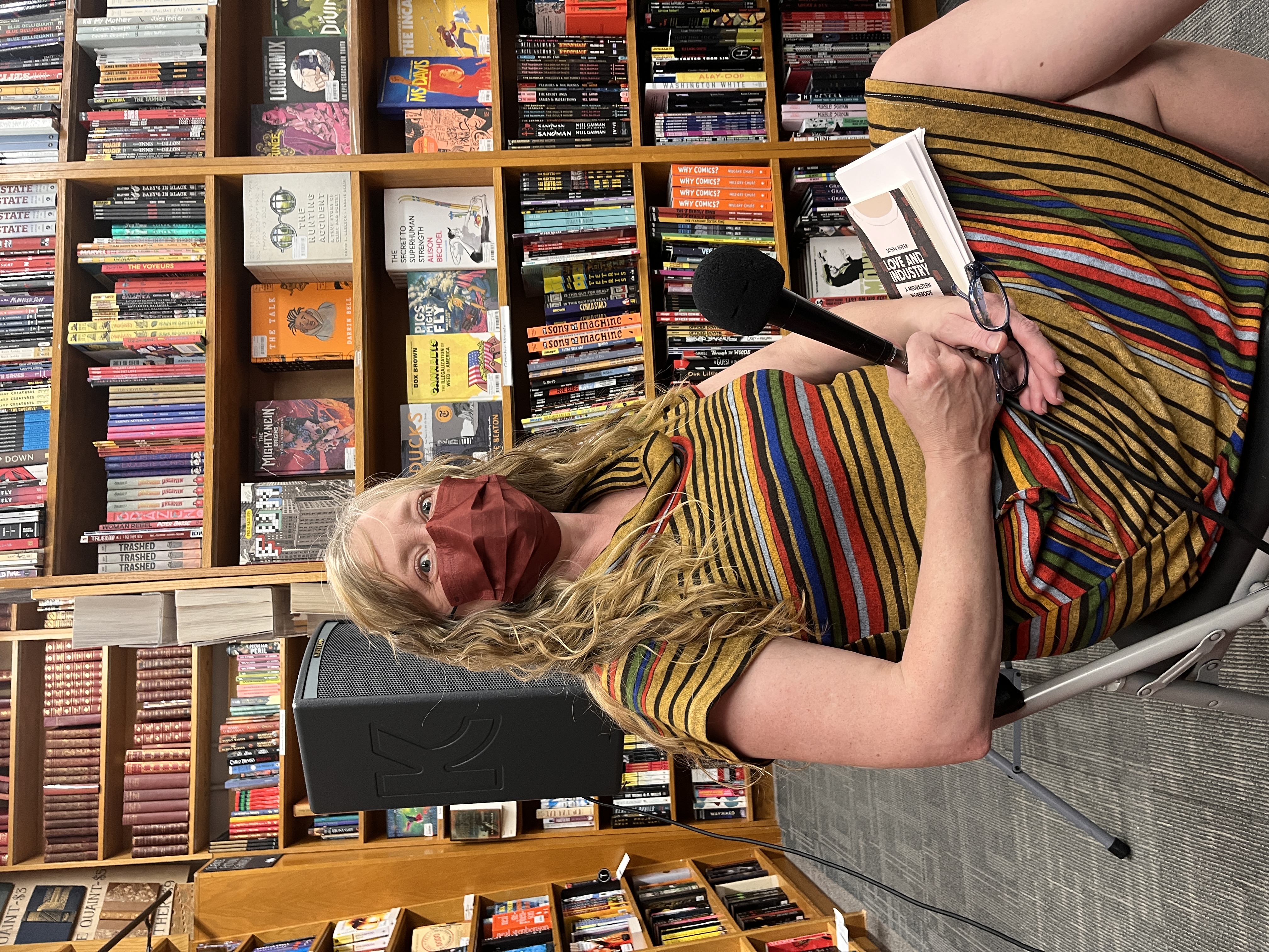 Kate Hopper wearing a mask and seated in front of bookshelves and a speaker at Magers & Quinn