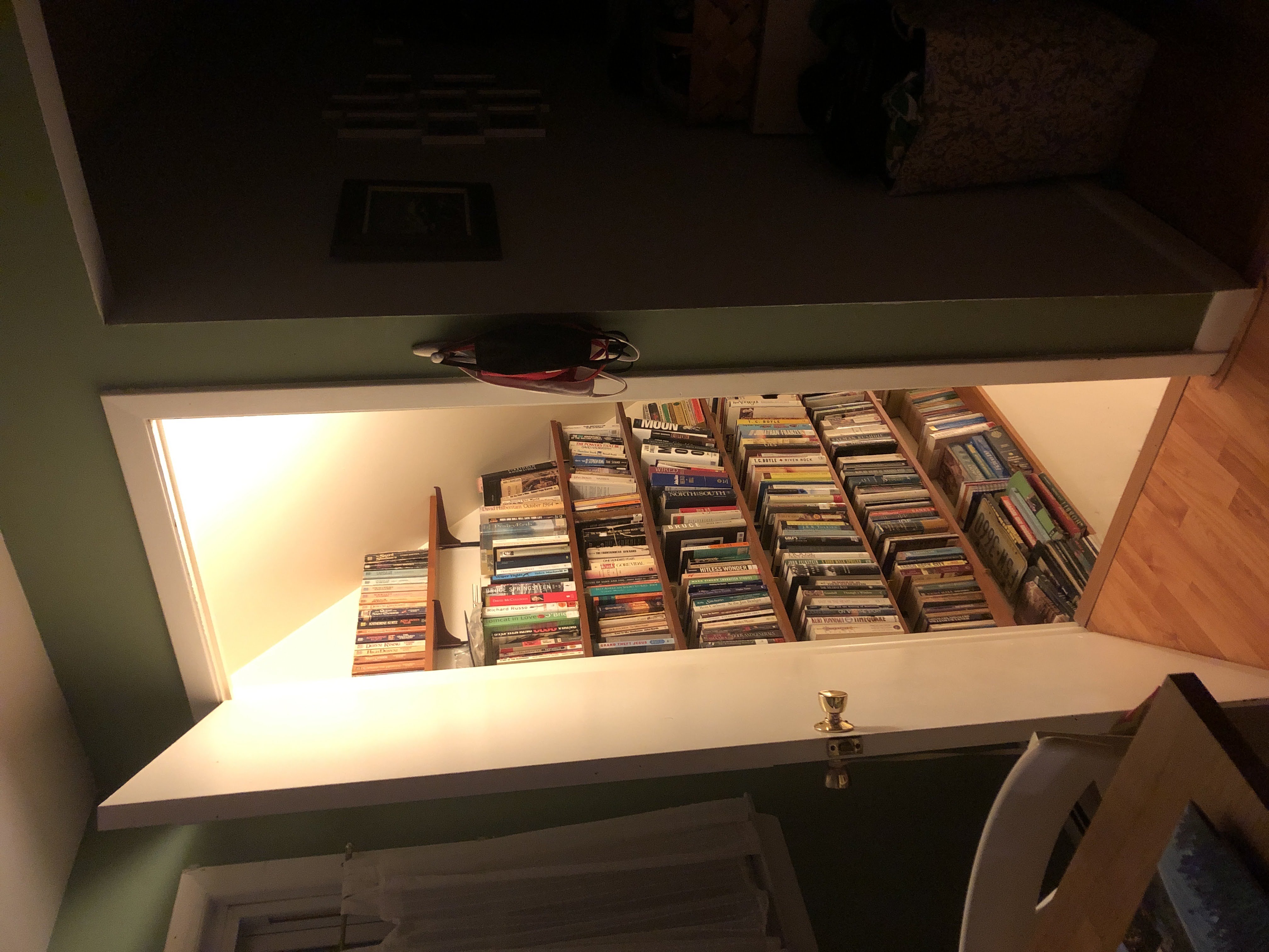Open doorway into a lit stairwell lined with bookshelves
