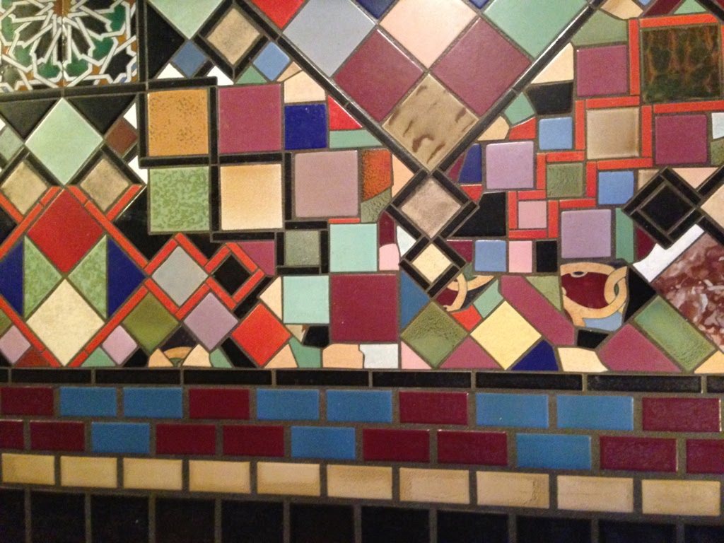 A very wild floor mosaic made of scrap floor tiles in black, orange, gray, mauve, greens and patterns.