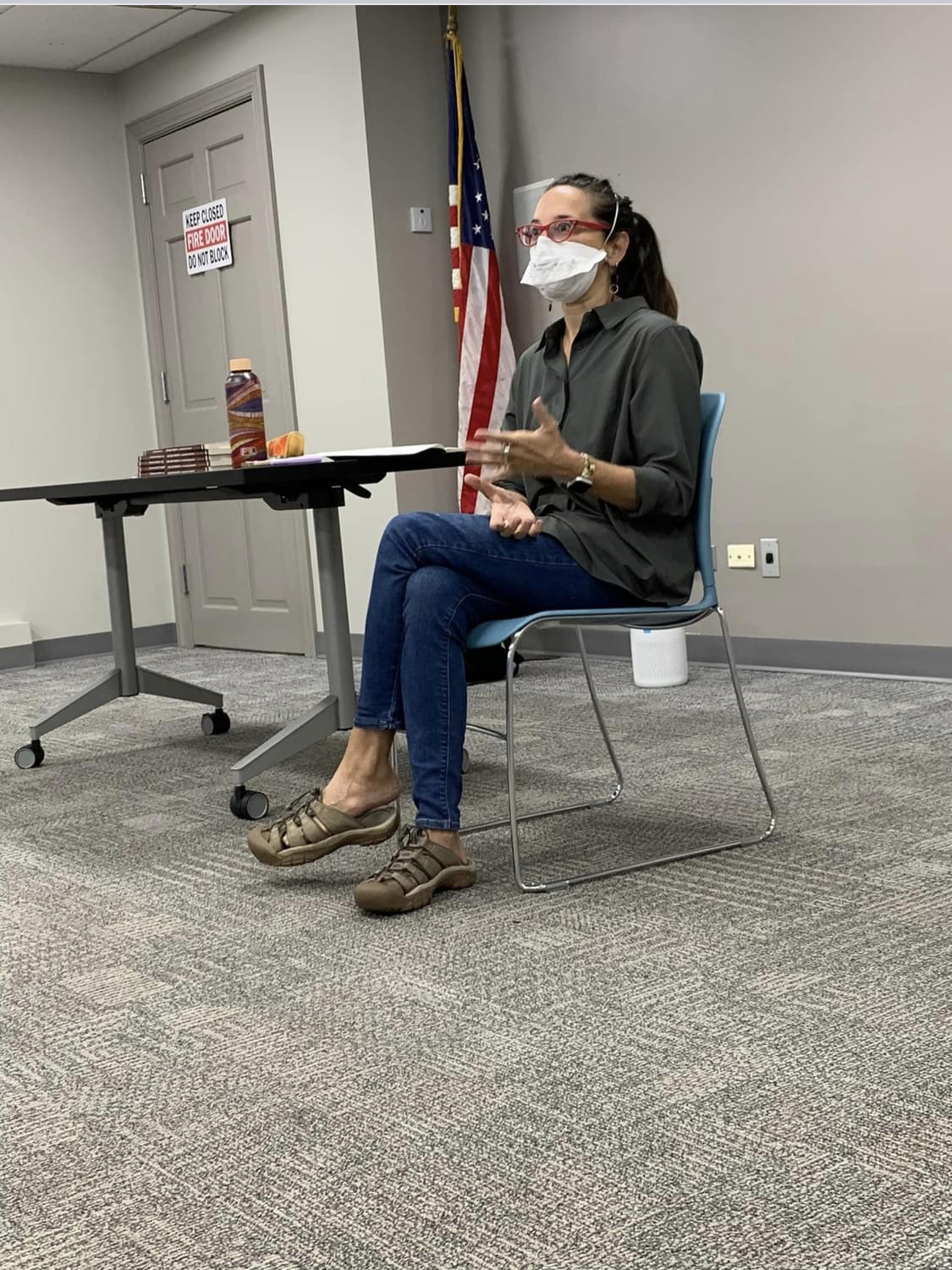 Sonya sitting in a chair with legs crossed wearing a mask